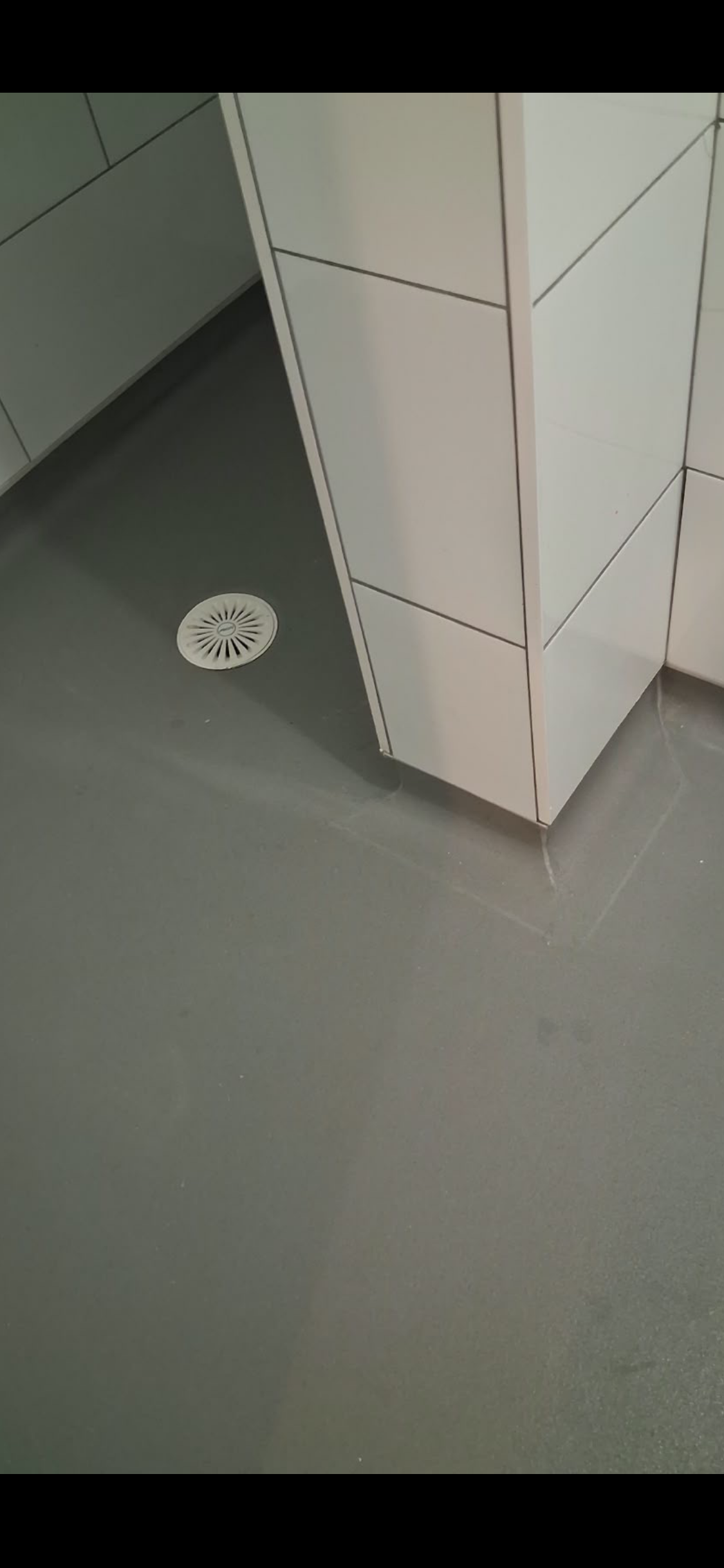 Coved vinyl flooring fitted around the base of a tiled partition