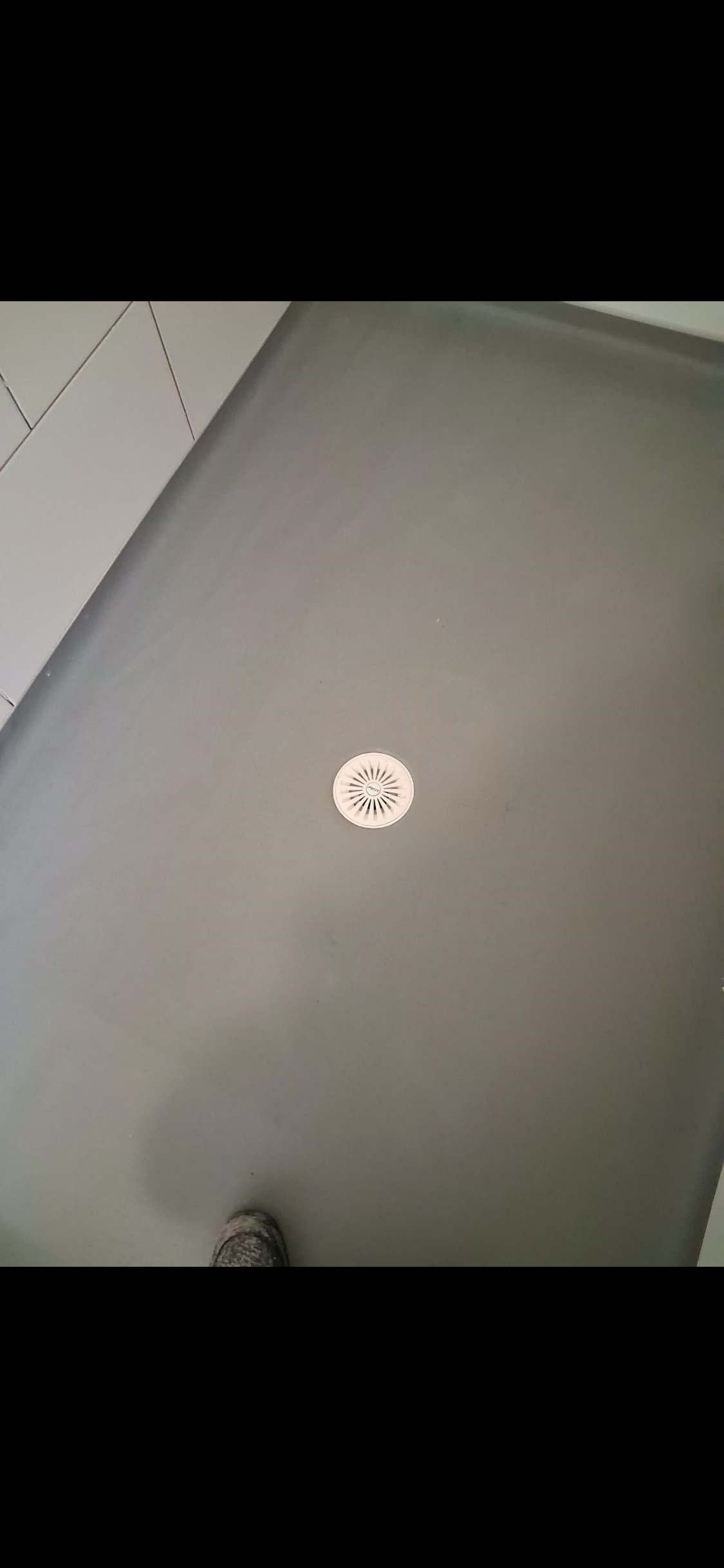 Grey wet-room floor and white circular shower drain